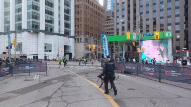 Toronto, ON, Kanada - 18 Ekim 2025: Bir polis memuru ve K9 birimi köpeği şehir maratonu başlamadan önce boş, kapalı cadde rotasında devriye geziyorlar.