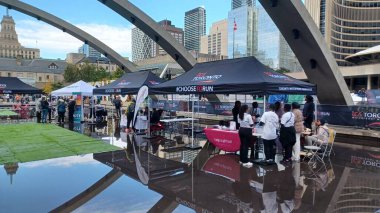 Toronto, ON, Kanada - 18 Ekim 2025: Bir belediye binasının sembolik kemerleri, satıcı çadırlarıyla düzenlenen bir maraton etkinliği sırasında bir havuza yansıyor