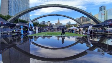 Toronto, ON, Kanada - 18 Ekim 2025: Bir belediye binasının sembolik kemerleri, satıcı çadırlarıyla düzenlenen bir maraton etkinliği sırasında bir havuza yansıyor