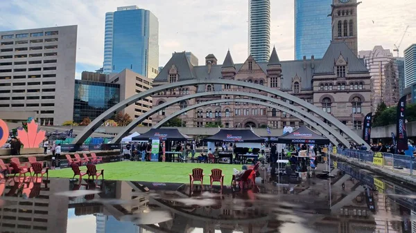 Toronto, ON, Kanada - 18 Ekim 2025: Bir belediye binasının sembolik kemerleri, satıcı çadırlarıyla düzenlenen bir maraton etkinliği sırasında bir havuza yansıyor