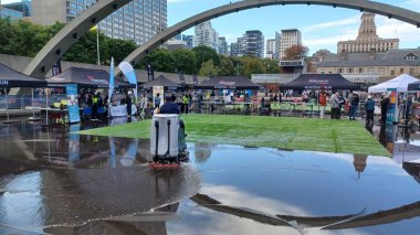 Toronto, ON, Kanada - 18 Ekim 2025: Bir belediye binasının sembolik kemerleri, satıcı çadırlarıyla düzenlenen bir maraton etkinliği sırasında bir havuza yansıyor