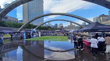 Toronto, ON, Kanada - 18 Ekim 2025: Bir belediye binasının sembolik kemerleri, satıcı çadırlarıyla düzenlenen bir maraton etkinliği sırasında bir havuza yansıyor