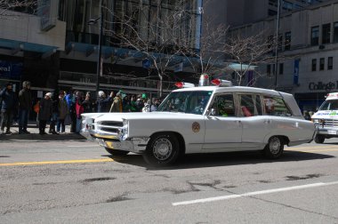 Toronto, ON, Kanada - 12 Ekim 2025: Beyaz antika bir acil durum aracı kaldırımdan izleyicilerin izlediği bir geçit töreninde şehir caddesinde ilerliyor.