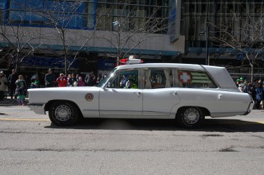 Toronto, ON, Kanada - 12 Ekim 2025: Beyaz antika bir acil durum aracı kaldırımdan izleyicilerin izlediği bir geçit töreninde şehir caddesinde ilerliyor.