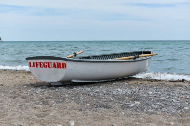Toronto, ON, Kanada - 12 Ekim 2025: Beyaz bir cankurtaran botu denizin yanındaki çakıllı bir sahilde, güvenlik görevine hazır..