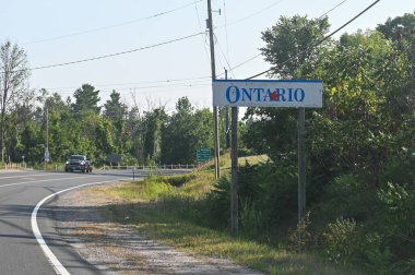 Ottawa, ON, Kanada - 3 Ekim 2025: Klasik bir Ontario il tabelası sınırı işaretliyor ve çevresi ağaçlarla çevrili kırsal bir yolda yolcuları karşılıyor.