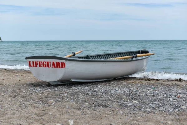 Toronto, ON, Kanada - 12 Ekim 2025: Beyaz bir cankurtaran botu denizin yanındaki çakıllı bir sahilde, güvenlik görevine hazır..