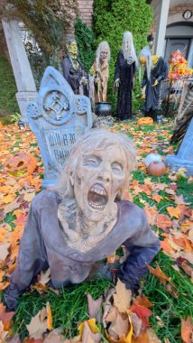 Toronto, ON, Kanada - 22 Ekim 2025 Yerden korkunç bir zombi süslemesi yükseliyor mezar taşları ve sonbahar yapraklarıyla dolu bir bahçede.