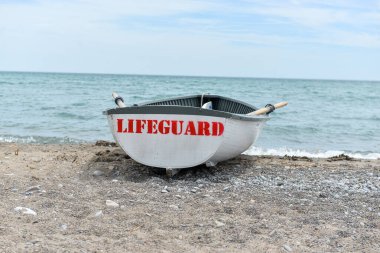 Toronto, ON, Kanada - 12 Ekim 2025: Beyaz bir cankurtaran botu denizin yanındaki çakıllı bir sahilde, güvenlik görevine hazır..