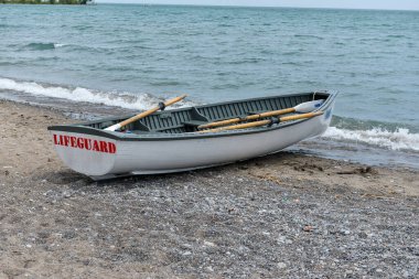 Toronto, ON, Kanada - 12 Ekim 2025: Beyaz bir cankurtaran botu denizin yanındaki çakıllı bir sahilde, güvenlik görevine hazır..