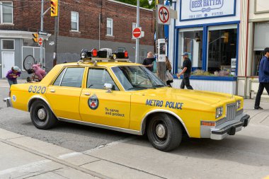 Toronto, ON, Kanada - 24 Ekim 2025: Klasik bir sarı metro polis arabası halka açık bir geçit töreninde şehir caddesinde ilerliyor.