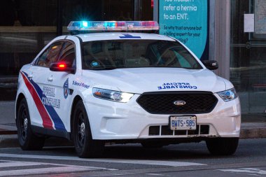 Toronto, ON, Kanada - 24 Ekim 2025: Şehrin bir caddesinde parlayan acil durum ışıkları olan beyaz bir özel polis arabası durduruldu.