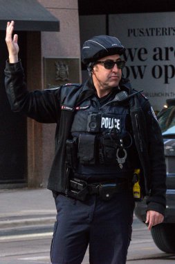 Toronto, ON, Kanada - 24 Ekim 2025: Emniyet yeleği giymiş bir polis memuru işlek bir şehir caddesinde araba trafiğini yönetti.