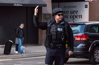 Toronto, ON, Kanada - 24 Ekim 2025: Emniyet yeleği giymiş bir polis memuru işlek bir şehir caddesinde araba trafiğini yönetti.