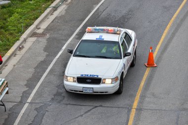Toronto, ON, Kanada - 24 Ekim 2025: Devriye gezen beyaz bir polis arabası yukarıdan görüldüğü gibi şehir caddesinde.