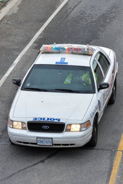 Toronto, ON, Kanada - 24 Ekim 2025: Devriye gezen beyaz bir polis arabası yukarıdan görüldüğü gibi şehir caddesinde.