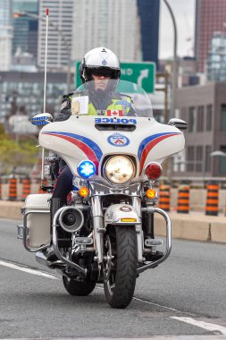 Toronto, ON, Kanada - 24 Ekim 2025: Kasklı ve güvenlik yeleği giymiş bir polis memuru şehir yolunda beyaz bir motosiklet sürüyor.