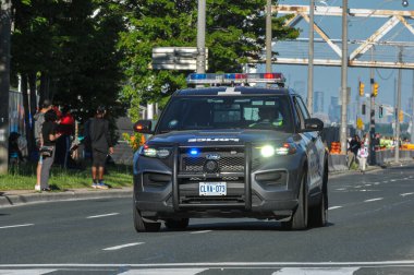 Toronto, ON, Kanada - 24 Ekim 2025: Bir polis cipi maraton koşucuları ile birlikte bir şehir caddesinde sürüyor.