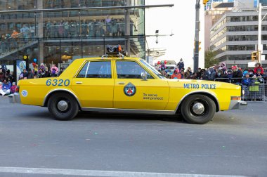 Toronto, ON, Kanada - 24 Ekim 2025: Klasik bir sarı metro polis arabası halka açık bir geçit töreninde şehir caddesinde ilerliyor.