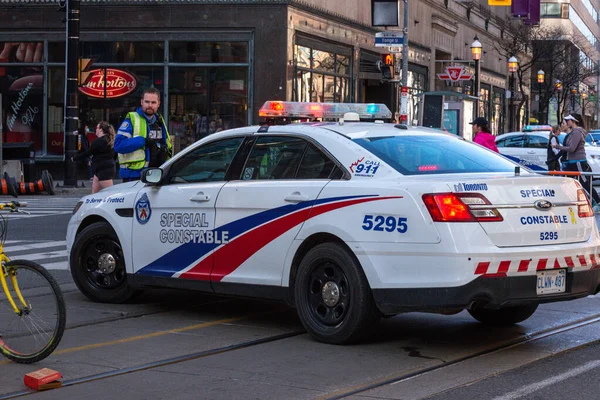 Toronto, ON, Kanada - 24 Ekim 2025: Şehrin bir caddesinde parlayan acil durum ışıkları olan beyaz bir özel polis arabası durduruldu.