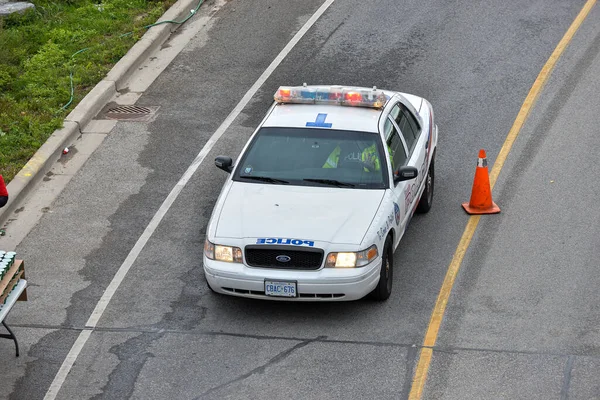 Toronto, ON, Kanada - 24 Ekim 2025: Devriye gezen beyaz bir polis arabası yukarıdan görüldüğü gibi şehir caddesinde.