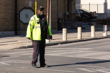 Toronto, ON, Kanada - 24 Ekim 2025: Göze çarpan ceketli bir polis memuru görevdeyken bir şehir caddesinde yürüyor.