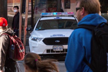 Toronto, ON, Kanada - 24 Ekim 2025: Şehrin bir caddesinde parlayan acil durum ışıkları olan beyaz bir özel polis arabası durduruldu.