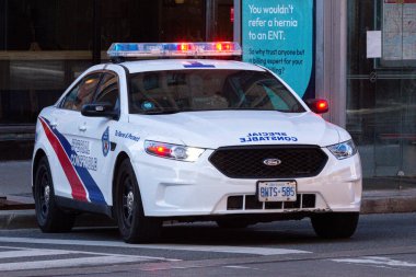 Toronto, ON, Kanada - 24 Ekim 2025: Şehrin bir caddesinde parlayan acil durum ışıkları olan beyaz bir özel polis arabası durduruldu.