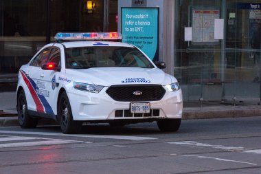 Toronto, ON, Kanada - 24 Ekim 2025: Şehrin bir caddesinde parlayan acil durum ışıkları olan beyaz bir özel polis arabası durduruldu.