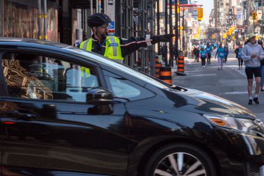 Toronto, ON, Kanada - 24 Ekim 2025: Emniyet yeleği giymiş bir polis memuru işlek bir şehir caddesinde araba trafiğini yönetti.