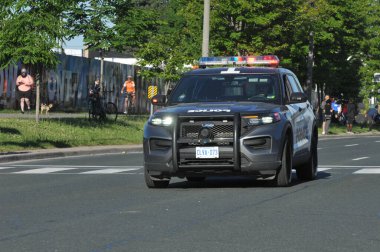 Toronto, ON, Kanada - 24 Ekim 2025: Bir polis cipi maraton koşucuları ile birlikte bir şehir caddesinde sürüyor.