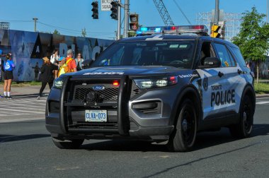 Toronto, ON, Kanada - 24 Ekim 2025: Bir polis cipi maraton koşucuları ile birlikte bir şehir caddesinde sürüyor.