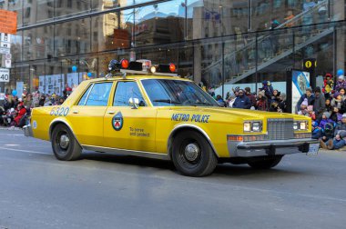 Toronto, ON, Kanada - 24 Ekim 2025: Klasik bir sarı metro polis arabası halka açık bir geçit töreninde şehir caddesinde ilerliyor.