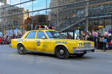 Toronto, ON, Kanada - 24 Ekim 2025: Klasik bir sarı metro polis arabası halka açık bir geçit töreninde şehir caddesinde ilerliyor.