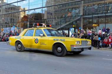 Toronto, ON, Kanada - 24 Ekim 2025: Klasik bir sarı metro polis arabası halka açık bir geçit töreninde şehir caddesinde ilerliyor.