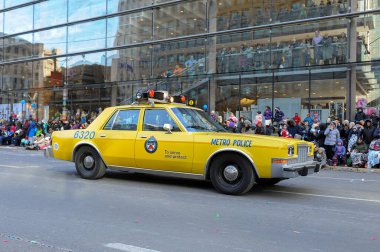 Toronto, ON, Kanada - 24 Ekim 2025: Klasik bir sarı metro polis arabası halka açık bir geçit töreninde şehir caddesinde ilerliyor.