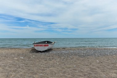 Toronto, ON, Kanada - 12 Ekim 2025: Beyaz bir cankurtaran botu denizin yanındaki çakıllı bir sahilde, güvenlik görevine hazır..