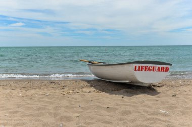 Toronto, ON, Kanada - 12 Ekim 2025: Beyaz bir cankurtaran botu denizin yanındaki çakıllı bir sahilde, güvenlik görevine hazır..