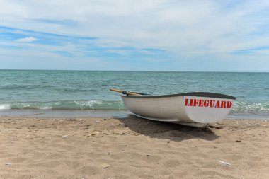 Toronto, ON, Kanada - 12 Ekim 2025: Beyaz bir cankurtaran botu denizin yanındaki çakıllı bir sahilde, güvenlik görevine hazır..