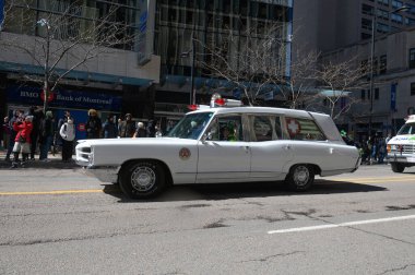 Toronto, ON, Kanada - 12 Ekim 2025: Beyaz antika bir acil durum aracı kaldırımdan izleyicilerin izlediği bir geçit töreninde şehir caddesinde ilerliyor.