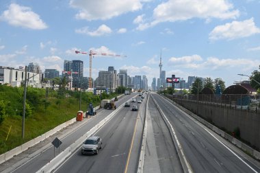 Toronto, ON, Kanada - 12 Ekim 2025: Şehir siluetine yaklaşan büyük bir otoyolda trafik akışı var..