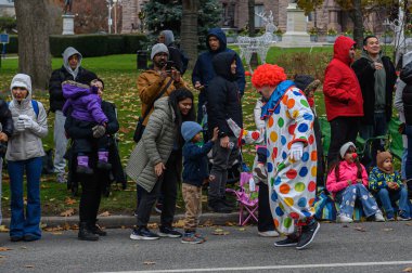 TORONONONONTO, ONTARIO, CANADA - 23 Kasım 2025: Benekli bir kostüm içindeki bir palyaço, orijinal Noel Baba Geçidi yolu boyunca çocuklar ve izleyicilerle etkileşim halindedir