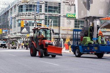Toronto, ON, Kanada - 18 Ekim 2025: Önden sabanla kırmızı bir traktör şehir caddesinde ilerliyor.