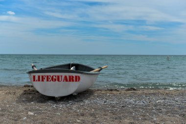 Toronto, ON, Kanada - 12 Ekim 2025: Beyaz bir cankurtaran botu denizin yanındaki çakıllı bir sahilde, güvenlik görevine hazır..