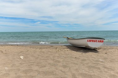 Toronto, ON, Kanada - 12 Ekim 2025: Beyaz bir cankurtaran botu denizin yanındaki çakıllı bir sahilde, güvenlik görevine hazır..