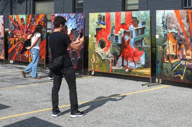 Toronto, ON, Kanada - 13 Eylül 2025: Canlı soyut resimleri gözlemleyen ve çeken katılımcılar, sanat ve topluluğu kutlayan bir kültür sokak festivalinde sergilendi