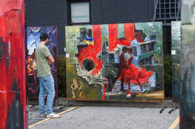 Toronto, ON, Kanada - 13 Eylül 2025: Ayakta duran, dans eden bir çiftin ve Ukrayna 'yı temsil eden soyut unsurların yer aldığı büyük tabloyu gözlemleyen adam, bir açık hava festivalinde sergilendi