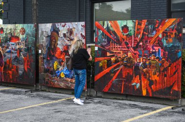 Toronto, ON, Kanada - 13 Eylül 2025: Bloor Ukrayna 'da bir sokak festivalinde sergilenen sanat eserlerini yakalayan kadın, kültür ve çatışmaları yansıtan duygusal tablolar sergileniyor