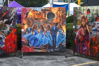 Toronto, ON, Kanada - 13 Eylül 2025: Yanan bir şehirden kaçan gençleri ve bir çocuğu tutan, savaşı, dayanıklılığı ve umudu sembolize eden bir kadını gösteren açık hava sergisi