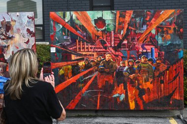 Toronto, ON, Kanada - 13 Eylül 2025: Bir kadın açık hava sokak festivalinde büyük, canlı bir tablo ve bir endüstriyel sahneyi akıllı telefonuyla çekiyor